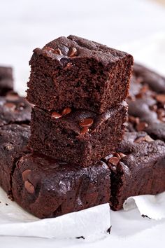 three chocolate brownies stacked on top of each other with one piece cut in half