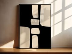 a black and white abstract painting on a wall in an empty room with sunlight coming through the window