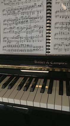 a piano with sheet music on it sitting in front of a keyboard that is black and white