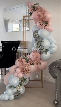 balloons and flowers are arranged in the shape of a spiral on a table next to a chair