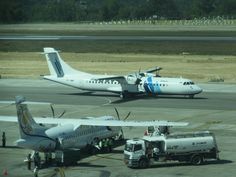 an airplane that is sitting on the tarmac with another plane in the back ground