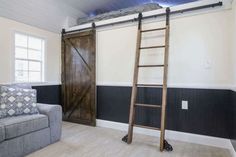 a living room with a couch, chair and ladder next to a sliding barn door