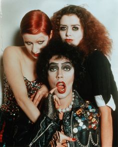 three women with makeup and hair are posing for the camera, one has her finger in her mouth