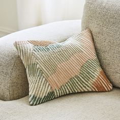 a pillow sitting on the back of a couch next to a white window sill