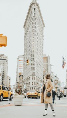 a woman crossing the street in front of a tall building