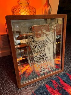 a decorative mirror sitting on top of a rug next to a vase with an angel drawn on it