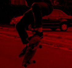 a skateboarder is doing a trick in the air with red light behind him