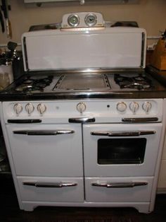 an old fashioned white stove with two burners and one oven door open in a kitchen