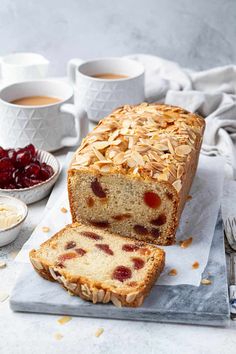 a loaf of bread sitting on top of a cutting board next to bowls of fruit