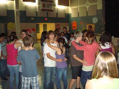 a group of people standing around each other in front of a sign that says nudele song dances