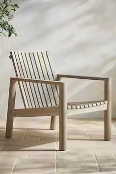 a wooden chair sitting on top of a tile floor next to a potted plant