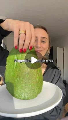 a woman is holding a large green object on a white plate with the caption, 2 ingredients match wrap