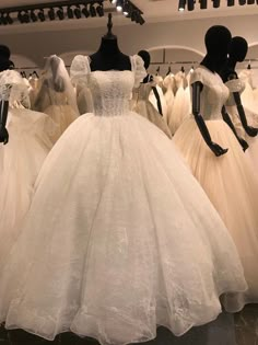 wedding gowns are on display in a store with mannequins behind them