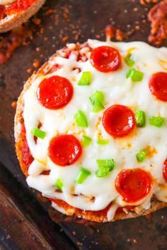 a pepperoni pizza on a cookie sheet with cheese and green onion sprinkles