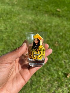 a person holding up a shot glass with an image of a woman on the side