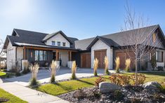 a large house with two garages and landscaping in front of the house on a sunny day