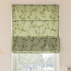 a window with a green floral roman blind in front of it and a lamp on the side