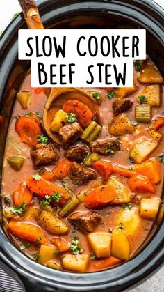 a wooden spoon in a slow cooker filled with beef stew and carrots,