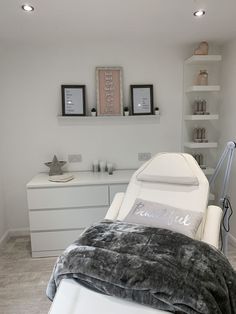 a white bed sitting in a bedroom next to a wall mounted shelf with pictures on it