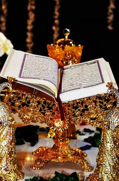 an open book sitting on top of a table next to some gold figurines