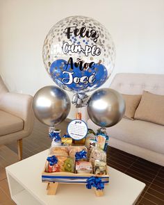 a table topped with balloons and gifts for someone's special occasion in the living room