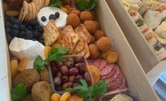 an open box filled with different types of food and snacks, including breads, crackers, grapes, meats, cheeses, and more