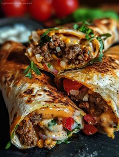 two burritos cut in half on a black plate