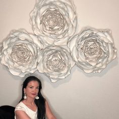 a woman sitting on a chair in front of a wall with paper flowers attached to it