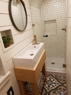 a white sink sitting under a mirror in a bathroom next to a walk in shower