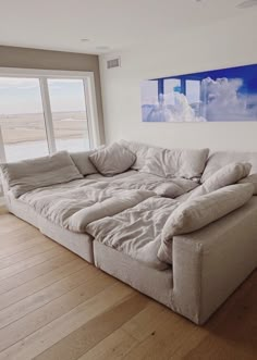 a large couch sitting in the middle of a living room next to a big window