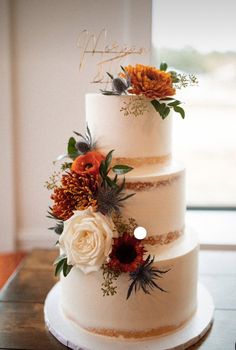 a three tiered wedding cake with flowers on top