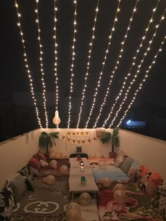 a living room filled with lots of furniture and lights hanging from the ceiling above it