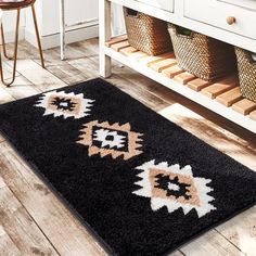 a black rug with an orange and white design on the floor next to a wooden table