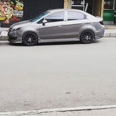 a silver car parked on the side of a road next to a man with a skateboard