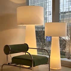 three lamps sitting next to each other in front of a window with a green chair