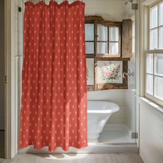 a bathroom with a red shower curtain next to a white bath tub