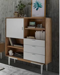 a white and wood cabinet with drawers in a room next to a plant on the wall