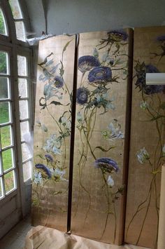 three panels with flowers painted on them in front of an open window, next to a piece of cloth