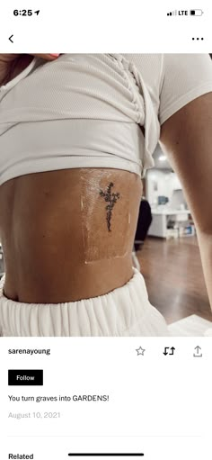 the back of a woman's stomach with a cross tattoo on her left side