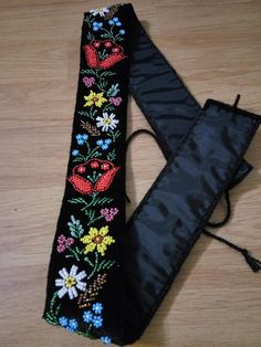 a black case with flowers and birds on it sitting on a wooden floor next to an umbrella