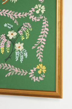 a painting with flowers painted on it in a gold frame, hanging on the wall