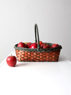 two apples are in a basket next to an apple on a white counter top,