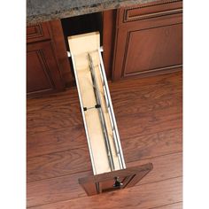 an open drawer in the middle of a kitchen with wooden flooring and brown cabinets