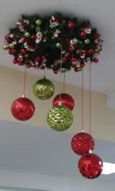 christmas ornaments hanging from the ceiling in front of a tree with red and green baubles