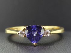 We are proud to offer you this exceptional ring with a magnificent trillion cut one carat royal blue Tanzanite. "Royal blue" is probably the best description for the intense shade of blue exhibited by this wonderful Tanzanite. Highly saturated, almost velvety.  Flanked either side are two bright white sparkling brilliant cut Diamonds, weighing 0.16 carats Finely handcrafted in 18 carat yellow Gold. Tanzanite is a member of the mineral family zoisite, which has been known about for nearly two cen Trillion Cut Sapphire Diamond Ring, Formal Tanzanite Trillion Cut Ring, Classic Formal Sapphire Ring With Trillion Cut, Classic Trillion Cut Sapphire Ring, Classic Trillion Cut Brilliant Sapphire Ring, Classic Sapphire Ring With Trillion Brilliant Cut, Formal Trillion-cut Sapphire Ring With Prong Setting, Trillion Cut Sapphire Rings For Formal Occasions, Formal Trillion Cut Sapphire Ring With Prong Setting