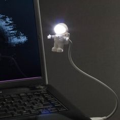 an open laptop computer sitting on top of a desk next to a white light bulb