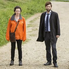 a man and woman standing on a dirt road