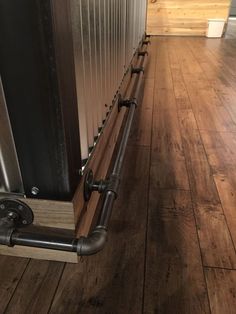 a wooden floor with metal pipes on the side and wood floors in front of it