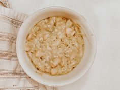 a white bowl filled with oatmeal sitting on top of a table next to a towel