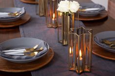 the table is set with gold and silver place settings, candles, and napkins